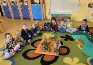 Dzieci siedzą i stoją zabawkowe dinozaury