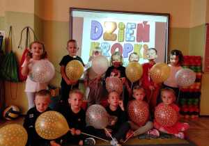 Dzieci z balonikami w kropki na tle napisu Dzień Kropki