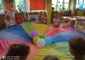 Dzieci bawią się kolorowa chustą.