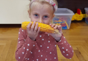 Hania trzyma kolbę kukurydzy i ją wącha.