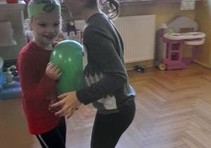 Paulinka i Magda tańczą, trzymając między sobą, zielony balon.