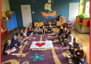 Dzieci z grupy Jeżyki siedzą dookoła tablicy z odkodowanym sercem